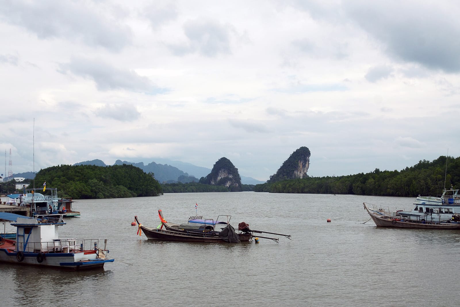 Krabi Town riverside, with the white clock tower and mangrove hills behind the roofs