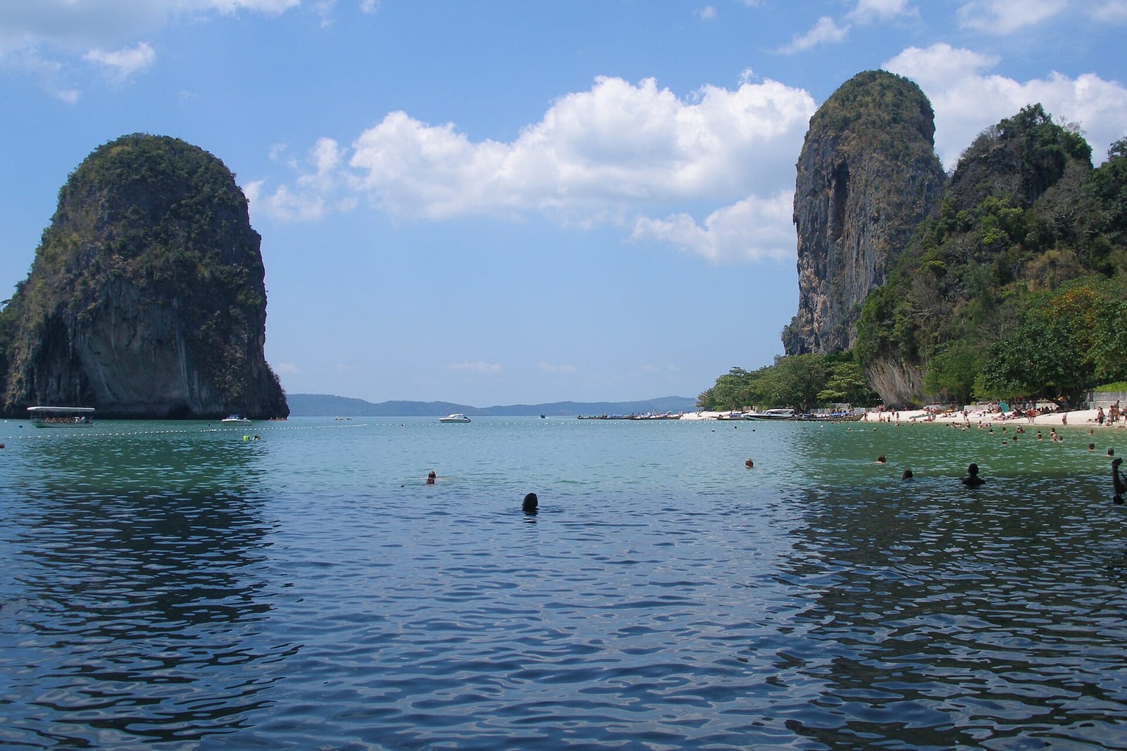 Limestone cliffs and a sandy cove at Railay in Krabi, with longtail boats near the shore