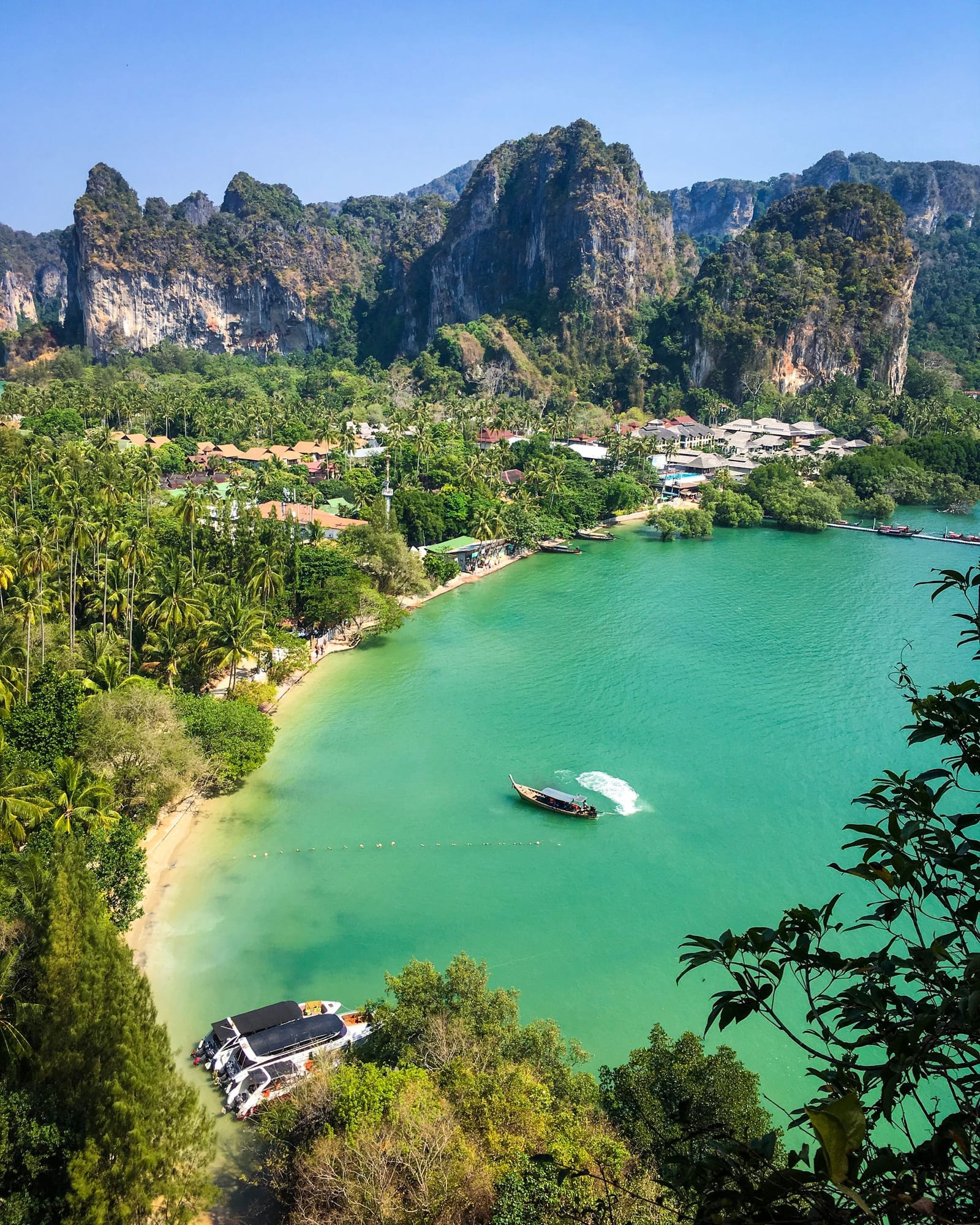 Longtail boats on the sand at Railay West, with the limestone headland behind them